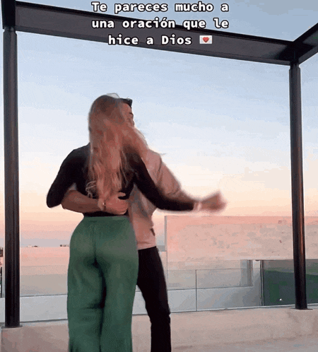 a man and a woman are dancing in front of a sign that says te pareces mucho a una oración