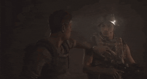 two men are looking at each other in the dark