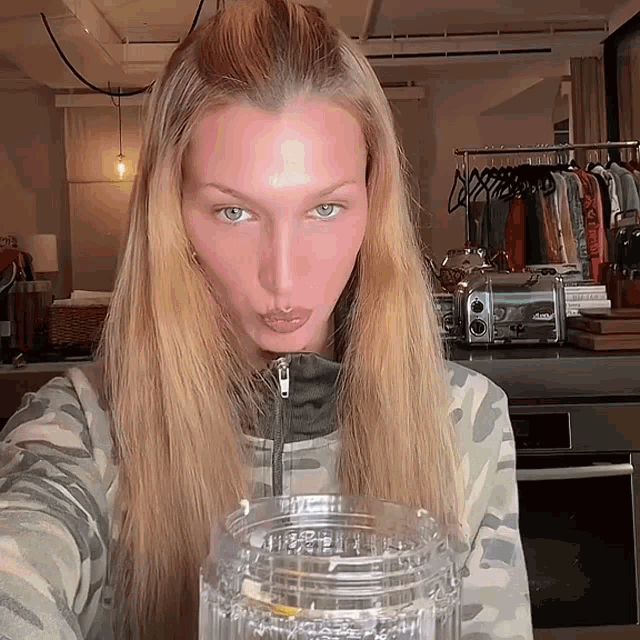a woman with long blonde hair is drinking from a clear glass