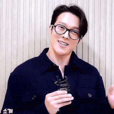 a man wearing glasses is smiling and holding something in his hand