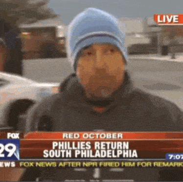 a man wearing a blue hat is talking into a microphone on a live fox news channel .