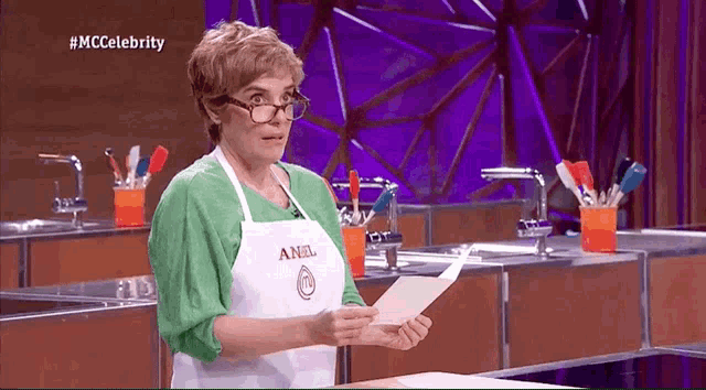 a woman wearing an apron that says anel holds a piece of paper
