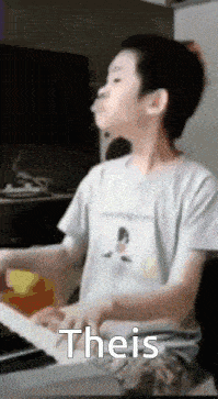 a young boy is playing a piano and making a funny face while wearing a white shirt .