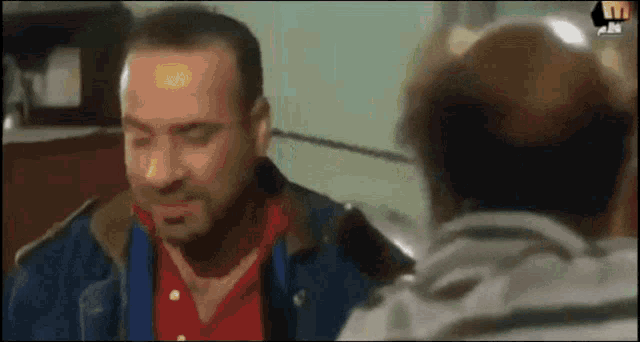 a man in a red shirt is talking to another man
