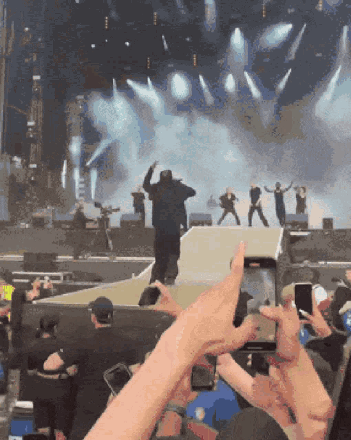 a group of people are taking pictures of a man on a stage at a concert