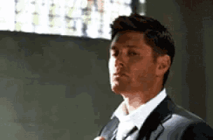 a man in a suit and tie is adjusting his tie in a room .