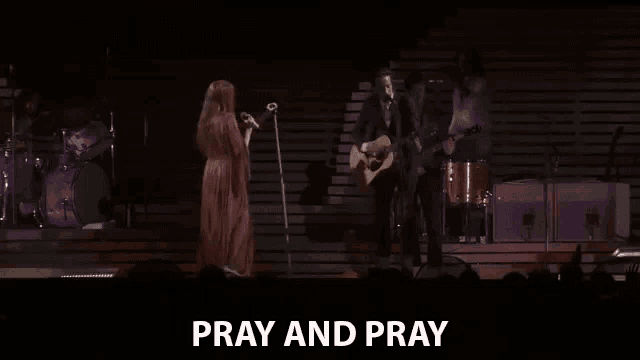 a woman singing into a microphone while a man plays a guitar on a stage .