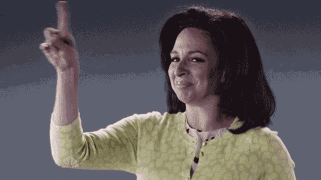 a woman in a yellow cardigan is pointing up