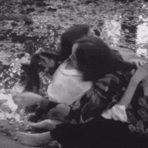 a black and white photo of a couple laying on the ground