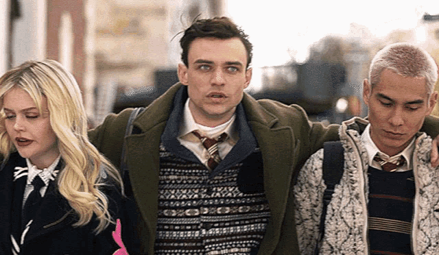 three people are walking down a street and one of them is wearing a sweater with a geometric pattern