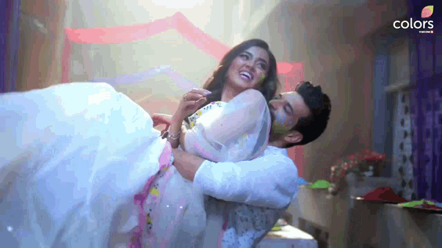 a man is carrying a woman in his arms and the words colors are on the bottom right