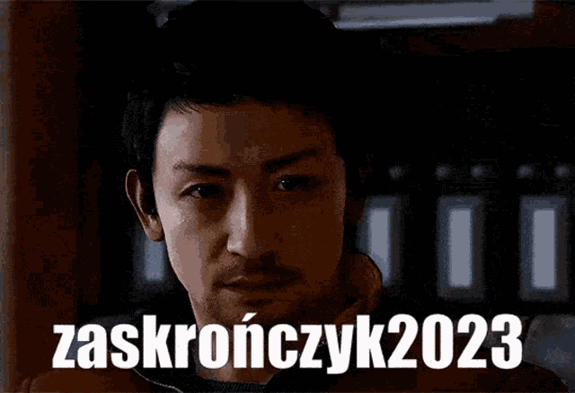 a man with a beard looks at the camera with the words zaskronczyk2023 above him