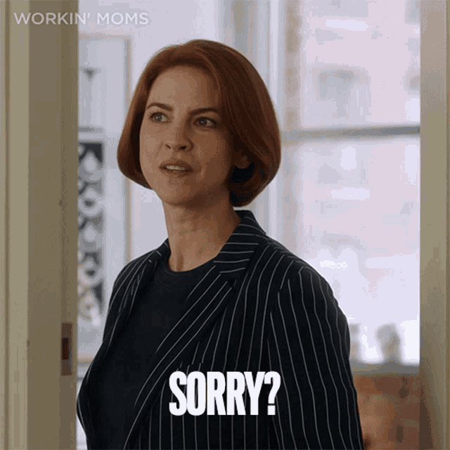 a woman in a suit says sorry in front of a window