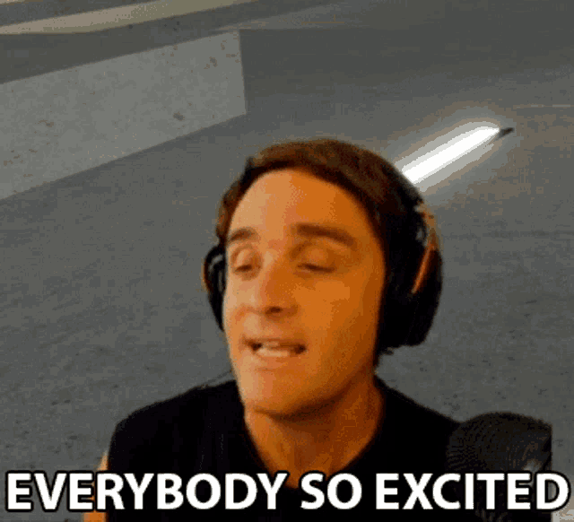 a man wearing headphones says everybody so excited in front of a microphone