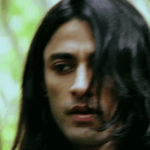 a close up of a man 's face with long hair