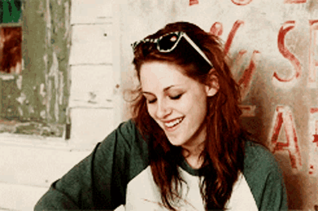 a woman wearing sunglasses is smiling in front of a wall with the letters s and a painted on it