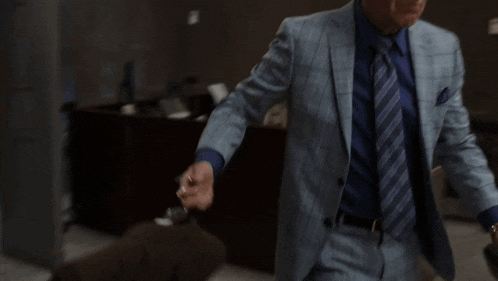 a man in a suit and tie stands in a hallway with his hands outstretched