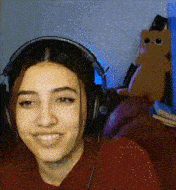a woman wearing headphones is smiling in front of a teddy bear