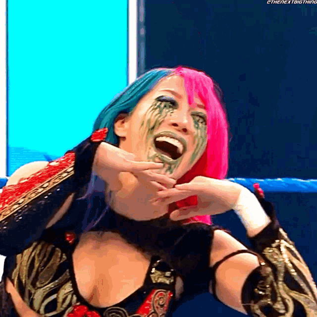 a woman with pink and blue hair is making a funny face with tears coming out of her eyes