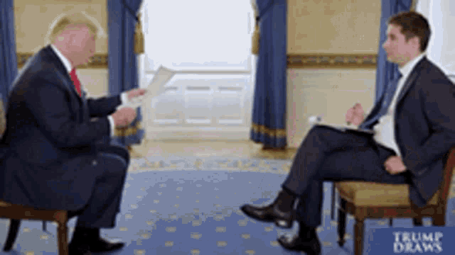 two men are sitting in front of a sign that says " trump draws "