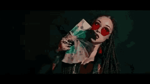 a woman with braids and red sunglasses is holding a bloody knife in her hand .