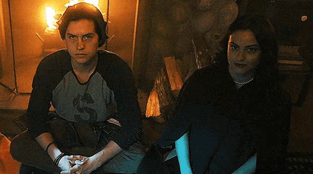 a man and a woman are sitting in front of a fireplace in a dark room .