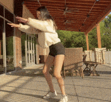 a woman in shorts is dancing on a patio