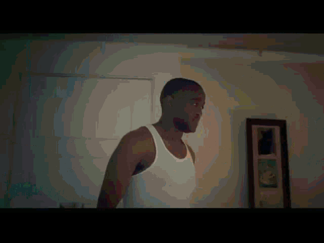a man in a white tank top stands in front of a mirror