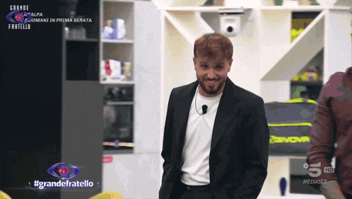 a man in a suit is standing in front of a sign that says #grandefratello