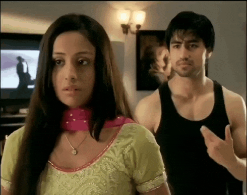 a man in a black tank top stands next to a woman in a green top