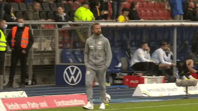 a man stands on a soccer field in front of a volkswagen ad