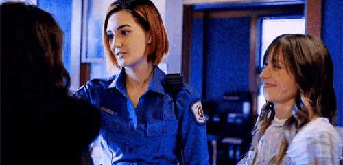a woman in a blue uniform is talking to another woman .
