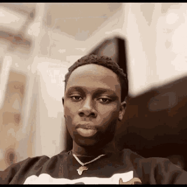 a young man wearing a necklace is taking a selfie .