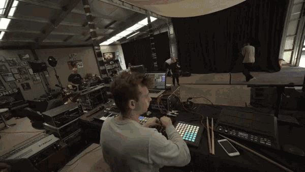 a man sits at a desk with a keyboard and a phone in front of a monitor that says ' korg ' on it
