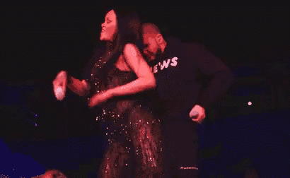 a man and a woman are standing next to each other on a stage . the woman is covering her face with her hand .