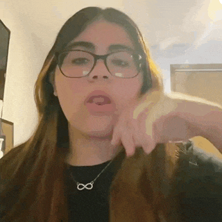 a girl wearing glasses and a necklace with an infinity symbol on it .