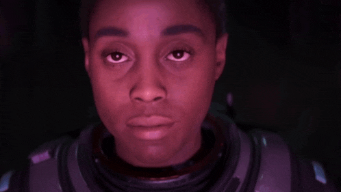 a close up of a woman 's face in a space suit looking at the camera .