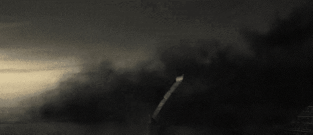 a dark landscape with a few trees in the distance