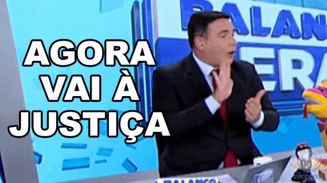 a man sitting in front of a sign that says agora vai a justicia