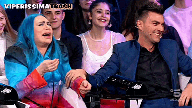 a woman with blue hair is laughing next to a man in a suit and the words viperissima trash are on the bottom