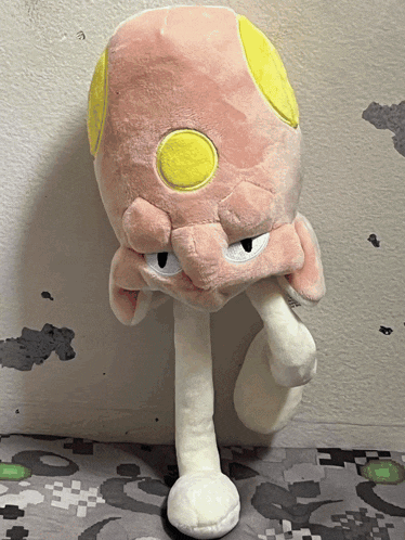 a stuffed animal with a yellow eye is sitting on a blanket