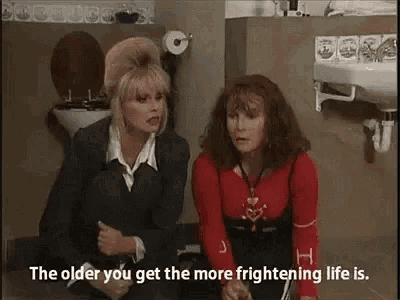 two women are sitting next to each other in a bathroom next to a toilet .
