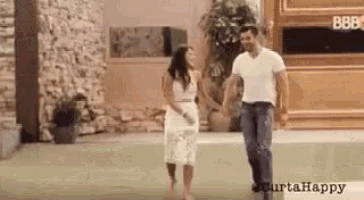 a man and a woman are holding hands while walking on a sidewalk .