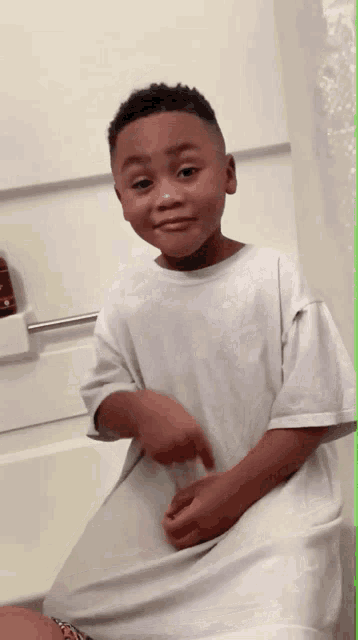 a young boy wearing a white shirt is sitting on a toilet