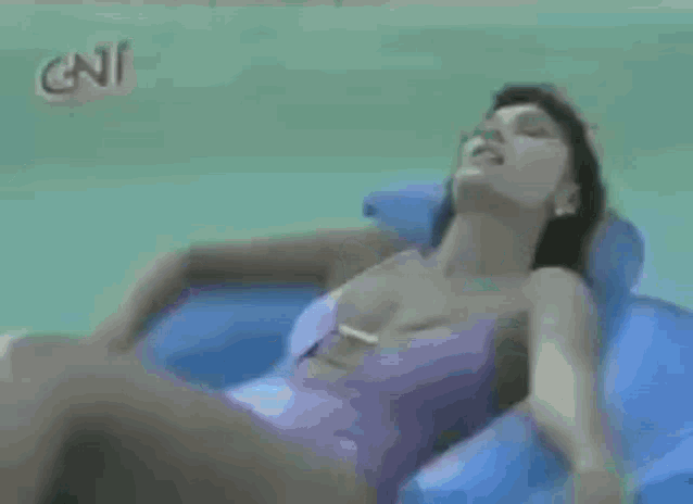 a woman in a pink bathing suit is laying on a blue raft in a swimming pool .