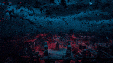 a flock of birds are flying over a cemetery in the dark