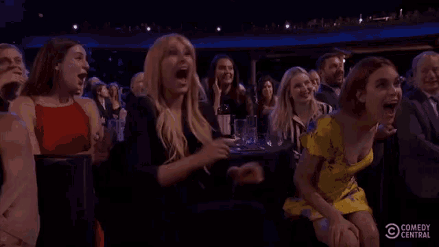 a group of women are sitting in a theatre applauding and laughing .