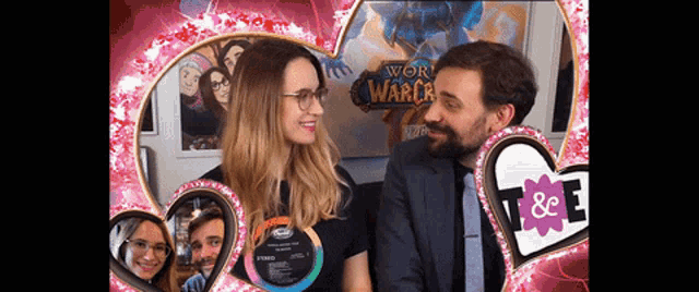a man and a woman are posing for a picture in front of a poster that says world of warcraft