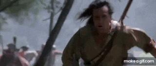 a man with long hair is running through a forest with a sword .