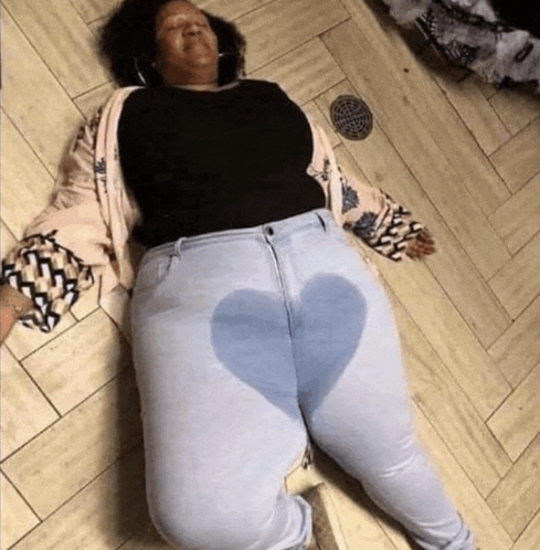 a woman is laying on the floor wearing a pair of jeans with a heart on the butt .